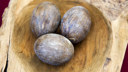 three brown wooden eggs in wooden bowl