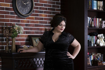 Plus size fashion model in black evening dress, fat woman on luxury interior, overweight female body