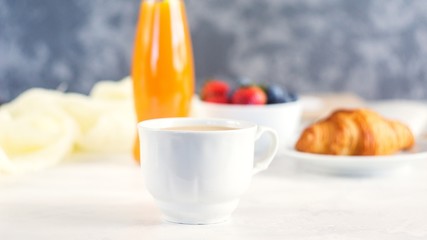 Cup of coffee, juice, fresh berries and croissants on white background. Morning breakfast