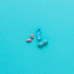 peanuts painted in blue near pink of nut. minimal flat lay. healthy food.