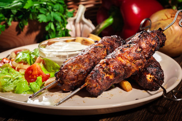 Grilled shish kebab served with fried chips and salad
