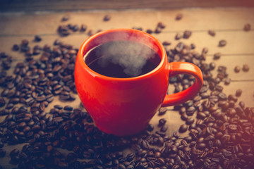 photo of beautiful cup of coffee near roasted beans on the wonderful brown wooden background