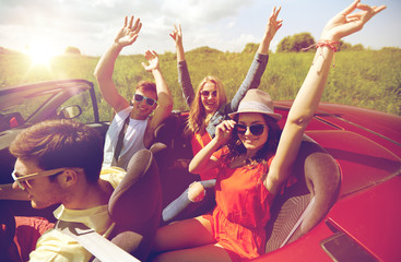 happy friends driving in cabriolet car at country
