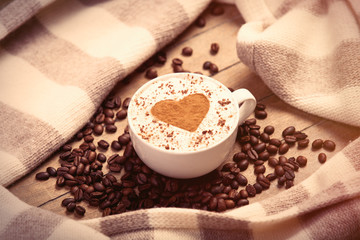 photo of cup of coffee, scarf and coffee beans on the wonderful brown wooden background