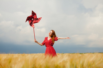 portrait of beautiful young woman with wind toy on the wonderful wheat field background