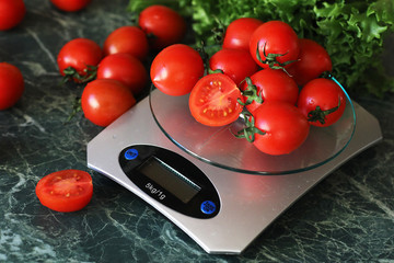 Fresh tomatoes on kitchen scales weighing