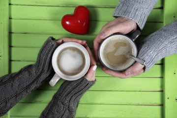 Young couple drinking hot coffee at wooden table on a date