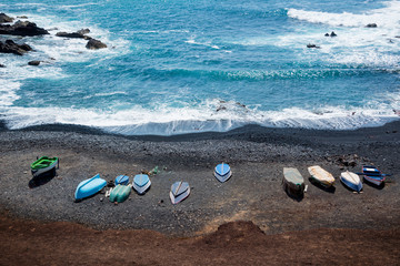 Fototapeta na wymiar Aerial view of colorful boats on a black sand beach in Lanzarote, Canary Islands, Spain