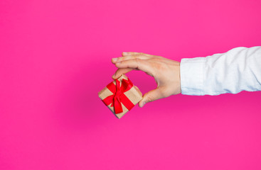 photo of male hand holding cute gift on the wonderful pink studio background