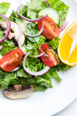 Salad of vegetables and champignons, lemon on white dishes close-up.