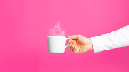 photo of male hand holding cup of coffee on the wonderful pink studio background