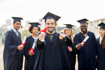 happy student with diploma pointing finger at you