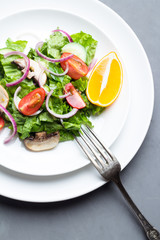 Vegetable salad with mushrooms on a white plate top view.
