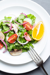 Vegetable salad with mushrooms on a white plate close-up.