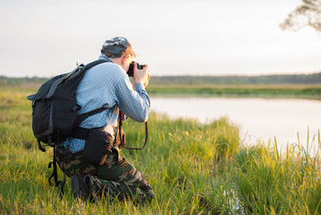 Male photographer looking at a lake during sunset,