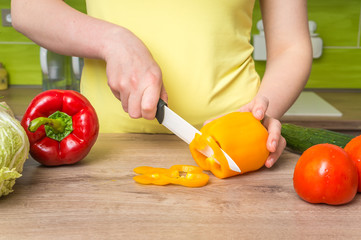 Woman cutting peppers for salad - fresh vegetables concept