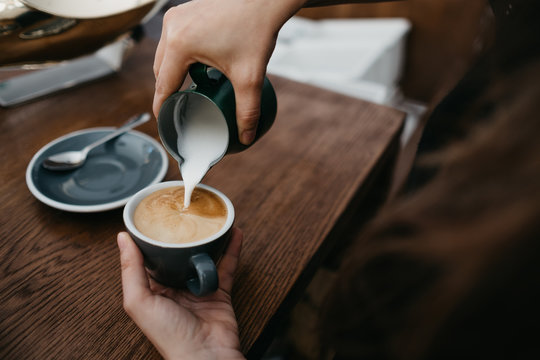 Person pouring milk to coffee