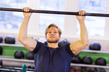 Naklejka premium man exercising on bar and doing pull-ups in gym