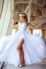 Sexy young blonde bride in a cruise wedding white dress in a summer sea restaurant
