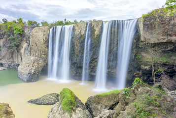 Fototapeta premium Natural waterfalls in the wild forest with high water flow down to the deep pool to create beautiful soft silk