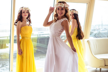 Beautiful Bride and two bridesmaids in yellow similar dresses together in a sea restaurant