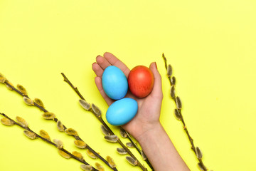 spring willow branch, female hand with colorful painted easter eggs