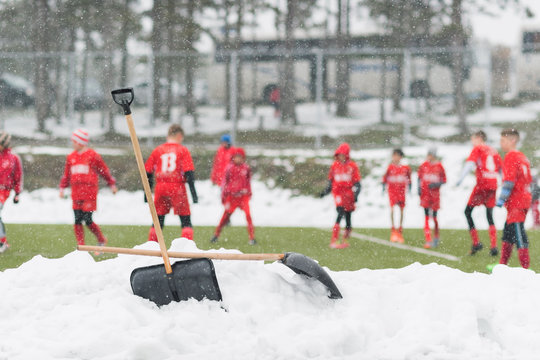 Shovels in the pile of snow after cleaning snow from the soccer field - kids soccer match during snow fall