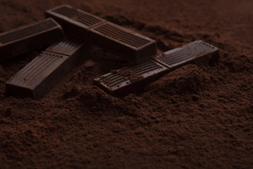 Close-up of chocolate bar pieces laying in chocolate powder