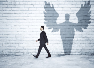 Walking businessman with angel shadow