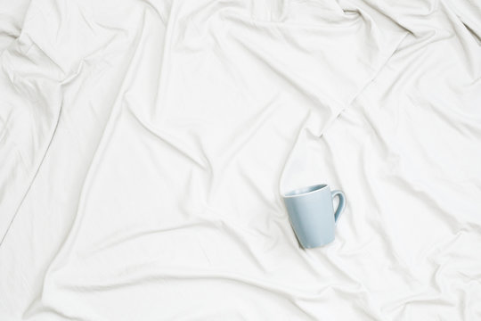 A blue mug on white cloth. Flat lay, top view. copy space
