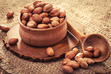 Peeled peanuts in a wooden bowl on an old burlap