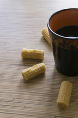 A cup of coffee with a pattern in the style of Khokhloma surrounded by small, roll wafers