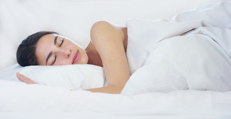 A simple day off for a beautiful young girl sleeping in a warm bed, covered with a soft warm white blanket, on a white background.