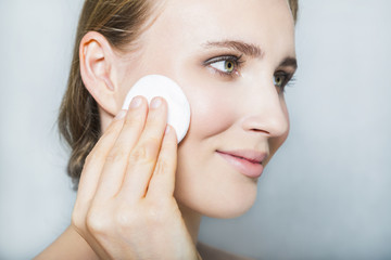 Face of young blonde beautiful girl with makeup and cotton pad