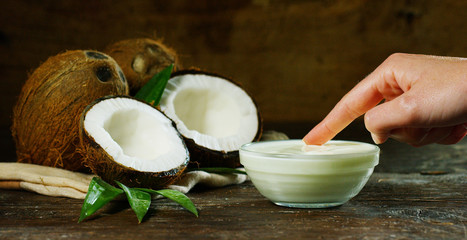 Fresh nourishing coconut milk moisturizing cream for hands, face and skin, on a dark wooden background, concept: spa, skincare, beauty, healthy lifestyle, bio products, ecologic products, massage.