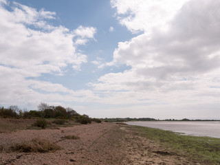 a landscape shot of the beach and sea with a cloudy blue sky and clear weather