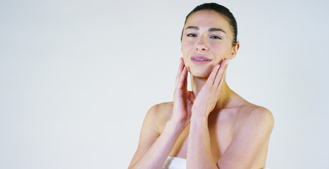 Portrait of a beautiful young girl massaging her face half a spa procedure, on a white background. Concept: spa products, spa massages, body care, harmony, love yourself, relax, loosen muscles.