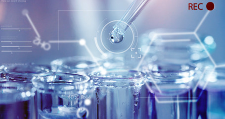 In a futuristic laboratory, a scientist with a pipette analyzes a colored liquid to extract the DNA and molecules in the test tubes.Concept:research,biochemistry,immersive technology,augmented reality