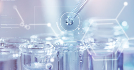 In a futuristic laboratory, a scientist with a pipette analyzes a colored liquid to extract the DNA and molecules in the test tubes.Concept:research,biochemistry,immersive technology,augmented reality