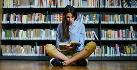 Portrait of a beautiful young woman smiling happy in a library holding books after doing a search and after studying. Concept: educational, portrait, library, and studious.