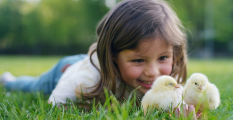 The best moments from life, the sweet girls, plays in the park with little chickens(yellow), on the background of green grass and trees, the concept: children, love, ecology, environment, youth. © Kitreel