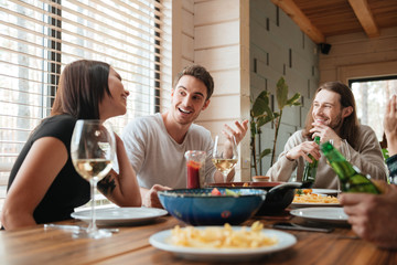 Group of happy people eating and talking at the table