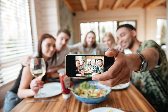 Group of friends having dinner and taking selfie with smartphone