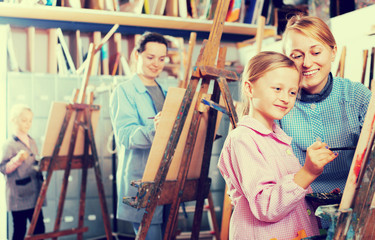 Obraz premium Female teacher helping girl during painting class