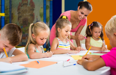 children sitting together and drawing in class at school