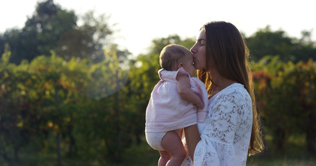 Fototapeta premium in a beautiful and happy sunny day , a mother and baby little girl play and are happy immersed in the colorful nature and happiness , the baby laughs happy . concept of happiness , love and nature. 