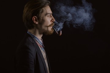 Studio portrait of a serious young businessman wearing a black suit on black background, copy space