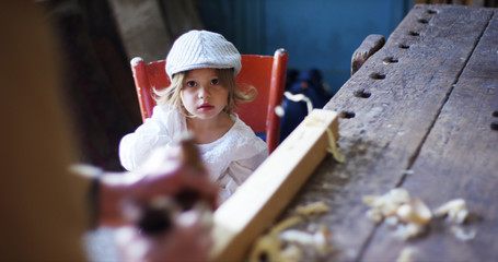 in an old carpentry shop a child and grandfather playing with a wooden airplane concept of tradition that continues over time	