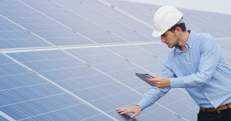 technical expert in solar energy photovoltaic panels, remote control performs routine actions for system monitoring using clean, renewable energy. concept of remote support technology. © Kitreel