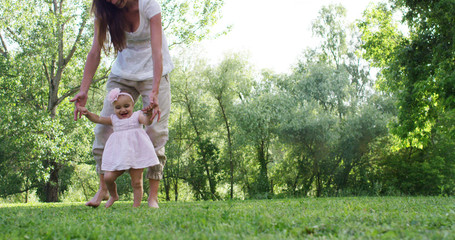 Fototapeta premium in a beautiful and happy sunny day , a mother and baby little girl play and are happy immersed in the colorful nature and happiness , the baby laughs happy . concept of happiness , love and nature. 